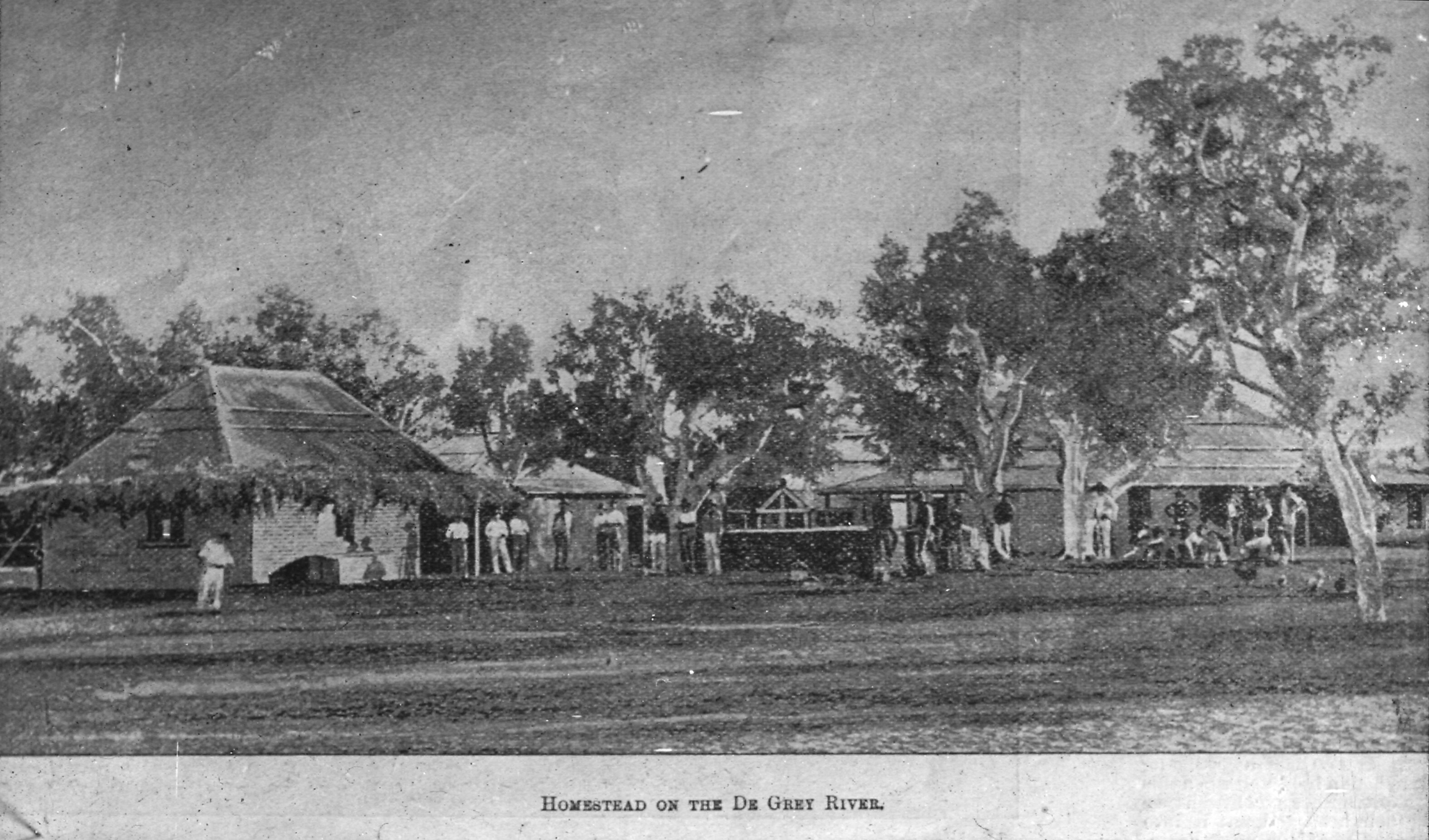 Black an white photo shows people and trees in front of buildings