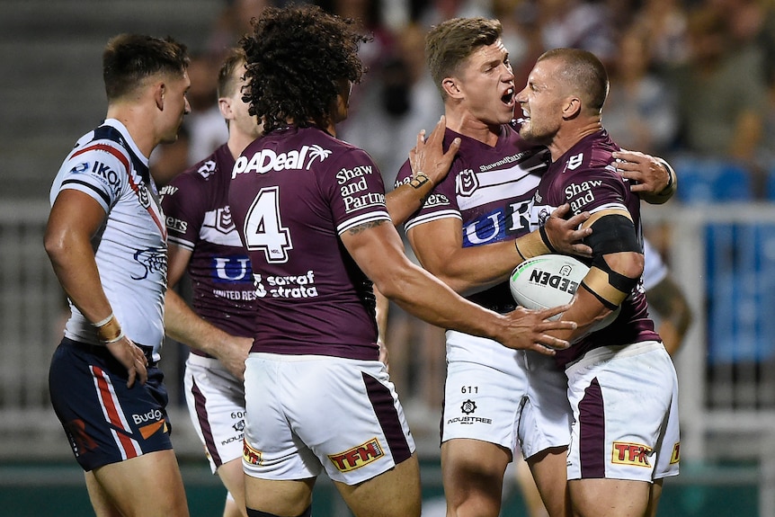 Four Manly NRL players celebrate scoring a try against the Sydney Roosters.