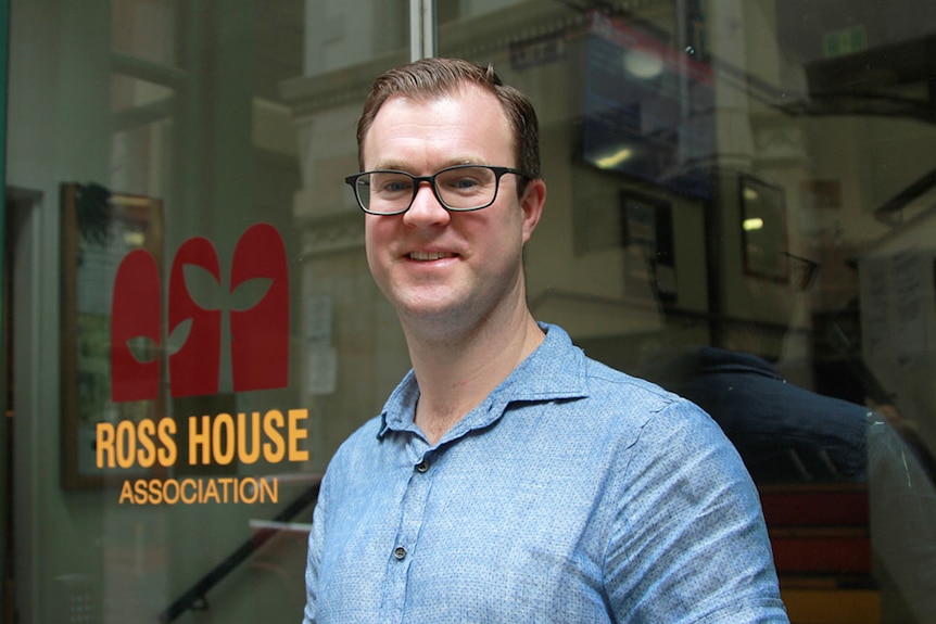 Ross House Association general manager Michael Griffiths smiles. The Ross House logo is on the glass doors behind him.