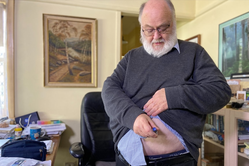 an elderly man administering an injection into his belly