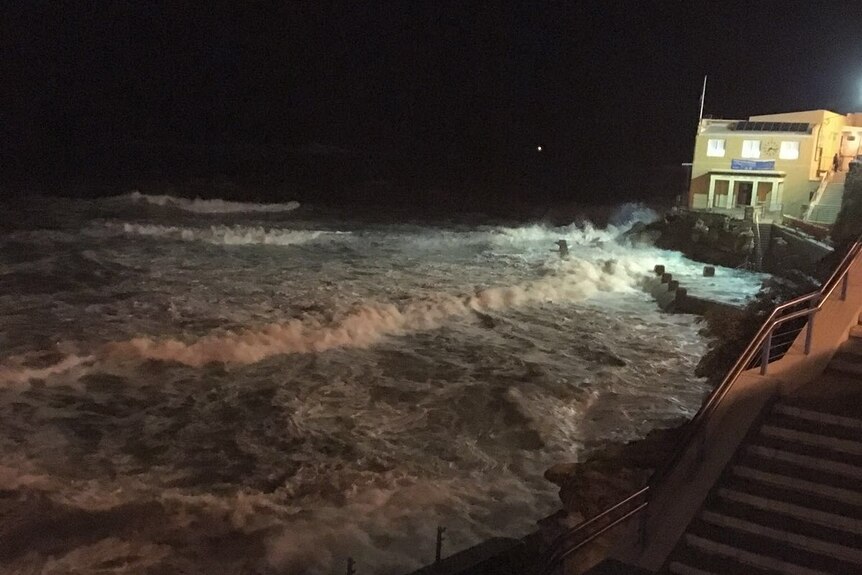 King tide and foamy, rough water at Coogee Beach in front of the surf club.