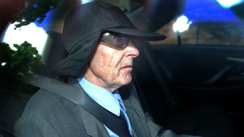 Convicted paedophile Dennis Ferguson is escorted by car into the Brisbane District Court