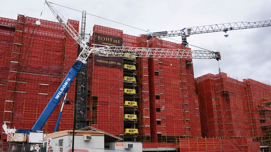 Two cranes next to a building under construction