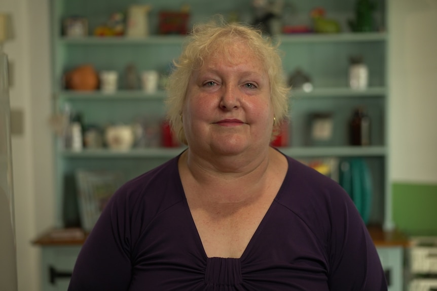 Woman wearing a purple shirt looking at the camera. 