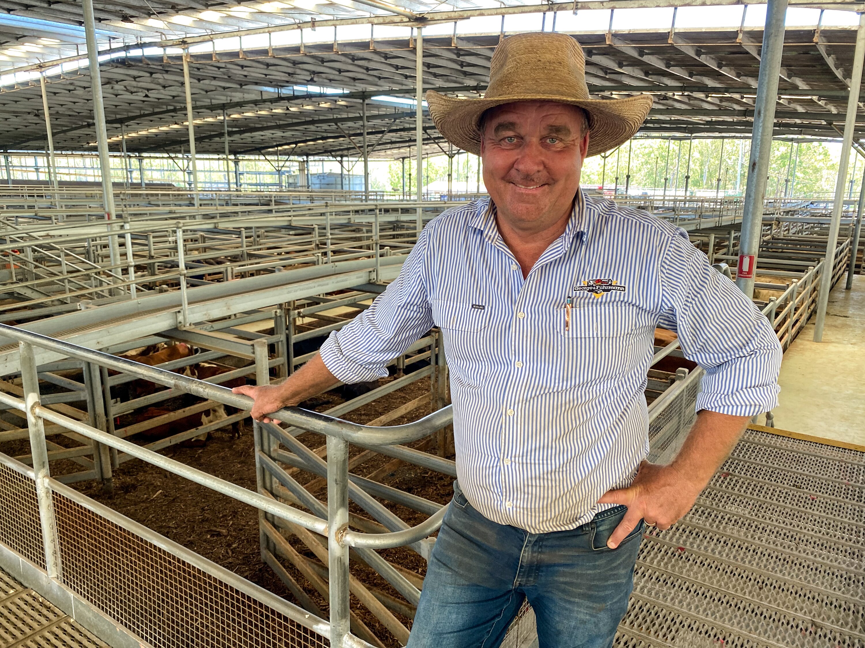 A man wearing a broad rimmed hat standing in a cattle yard.