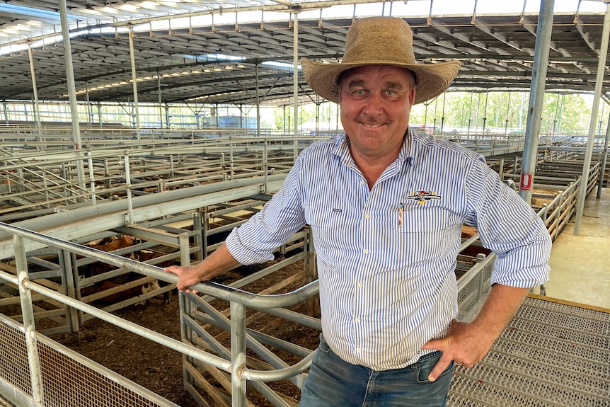 A man wearing a broad rimmed hat standing in a cattle yard.