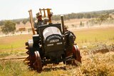 Tony Pailthorpe waves at eh camera as he drives one of his vintage tractors