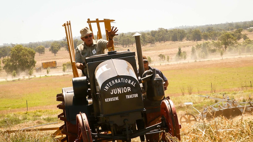 Tony Pailthorpe waves at eh camera as he drives one of his vintage tractors