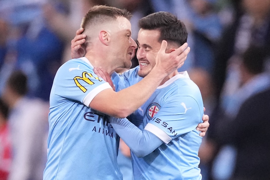Two Melbourne City A-League player embrace as they celebrate a goal.
