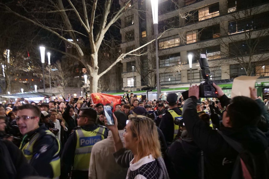 Police officers stand amid a crowd of people.