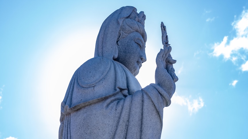 A photo of a Buddhist statue in front of blue skies.