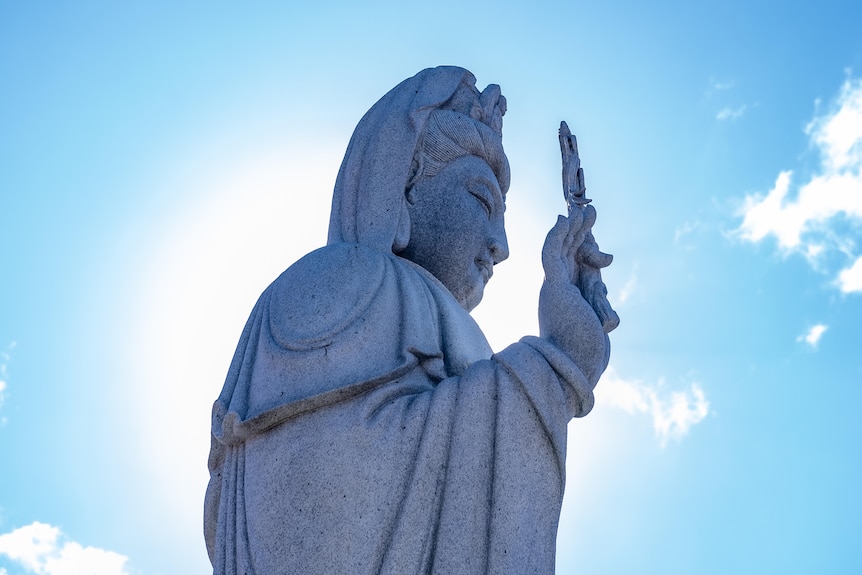 A photo of a Buddhist statue in front of blue skies.