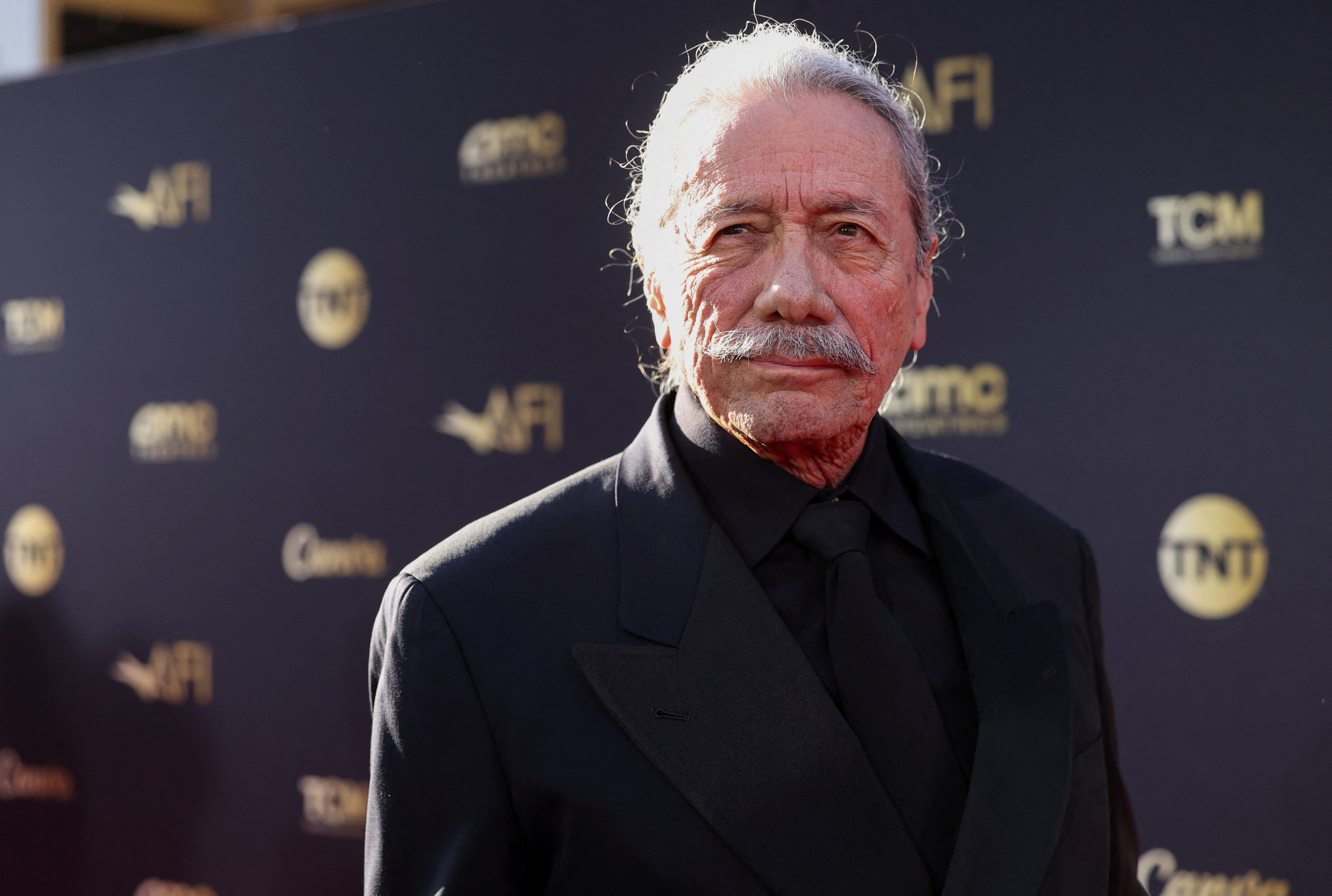 Edward James Olmos wearing a black suit with a black shirt and tie