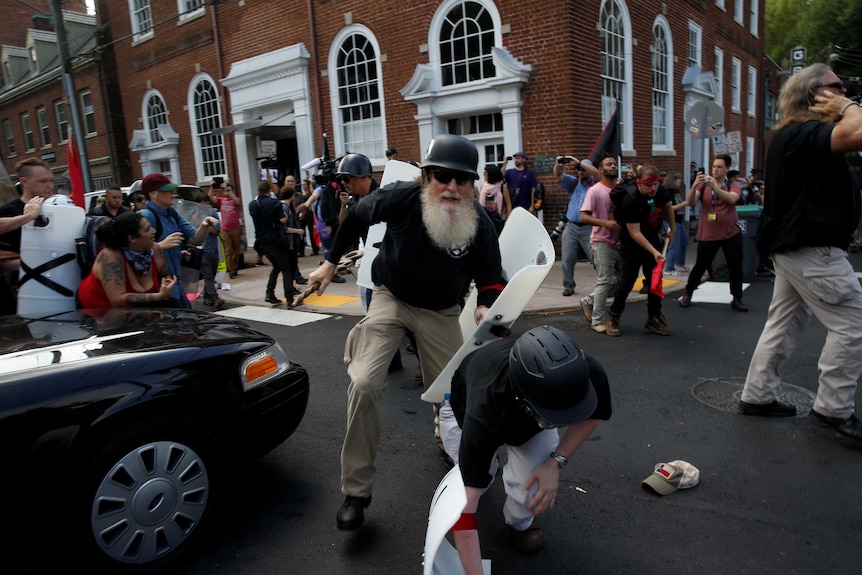 A white supremacist holds a makeshift riot shield during a clash with counter-protesters.