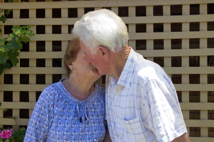 An elderly couple share a kiss.