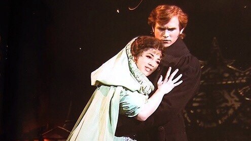 An actress on a stage in the arms of a male actor