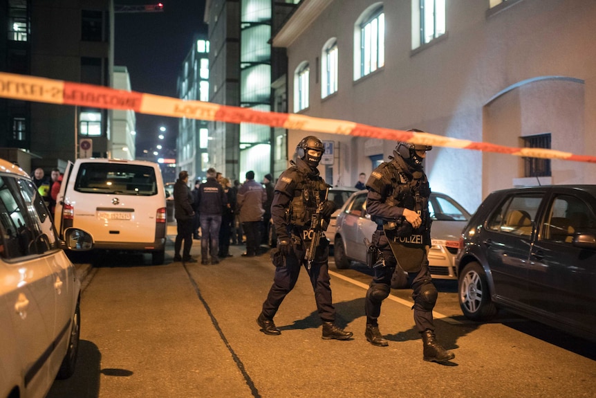 Special police walk behind a police tape line.