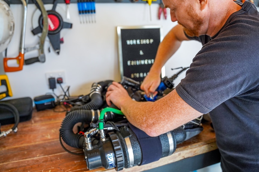 A man works on diving gear in a workshop.