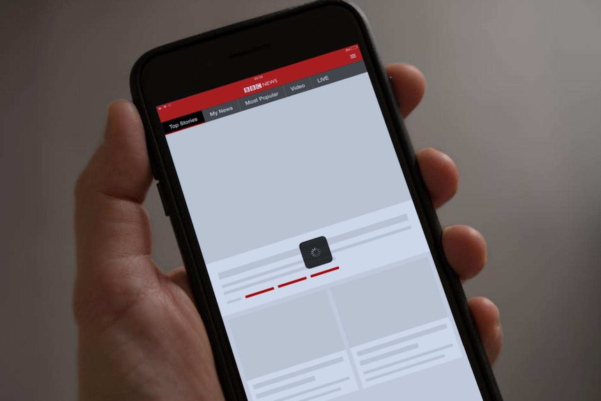 Hand holding mobile phone with BBC News website on screen unable to connect.