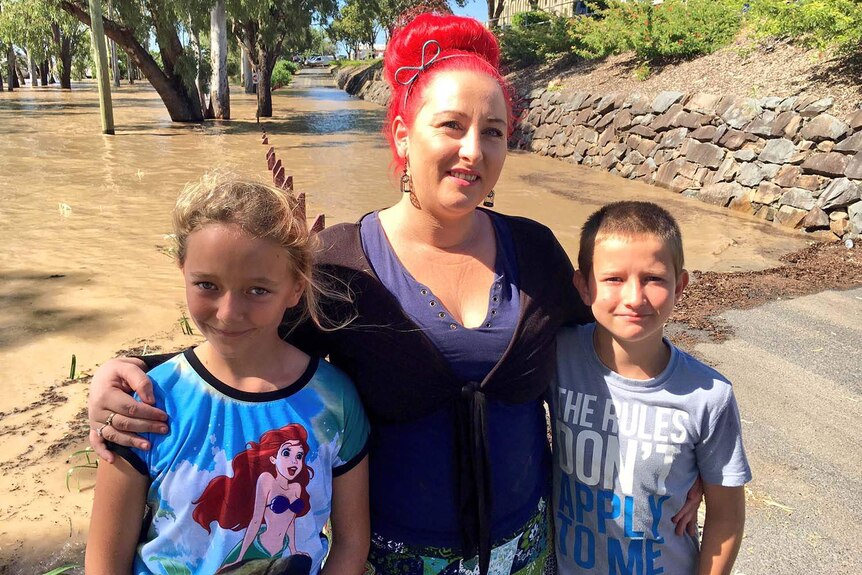 Depot Hill pub manager Tiona McGugian with her two kids at the edge of the flood