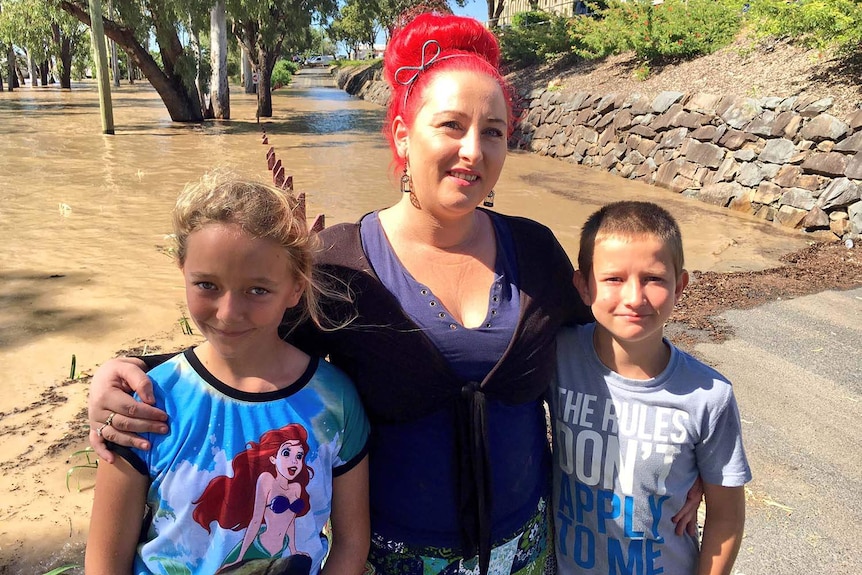 Depot Hill pub manager Tiona McGugian with her two kids at the edge of the flood