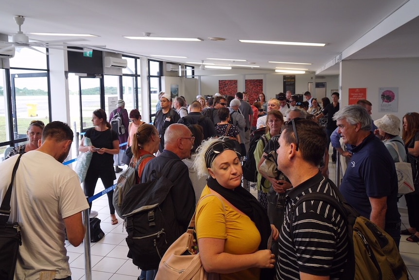 A group of people standing in line at Christmas Island airport.