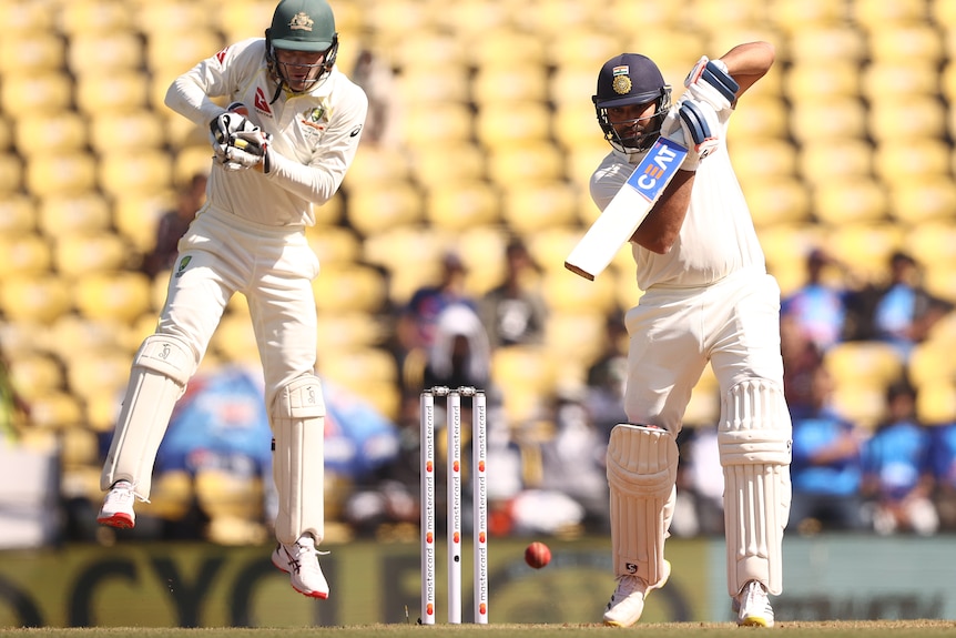 Rohit Sharma plays a cover drive as Alex Carey leaps up behind him