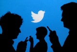 People on their phones silhouetted against a blue background with the Twitter icon on it