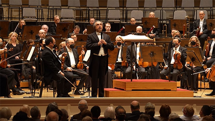 Riccardo Muti speaks from the stage in front of the Chicago Symphony Orchestra.
