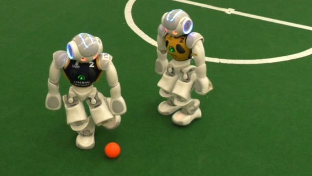 Two small robots play soccer
