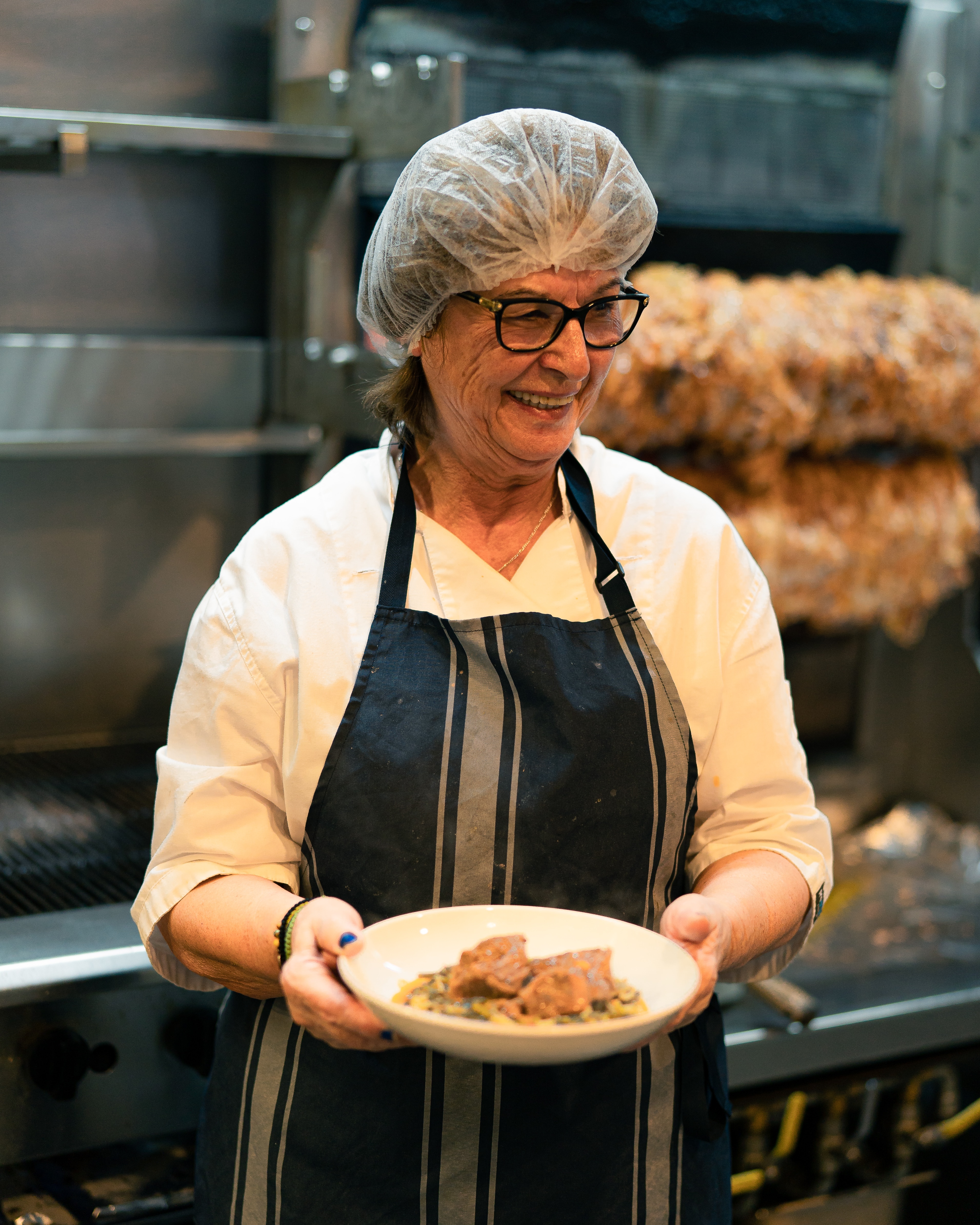 A woman wearing an apron and hairnet in the kitchen of Stalactites