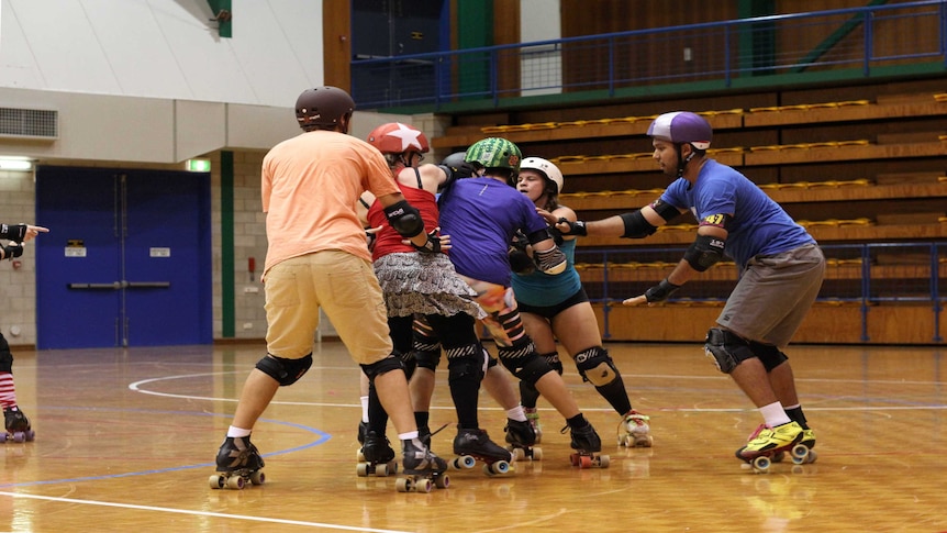 Men and women in skate gear on a basketball court.