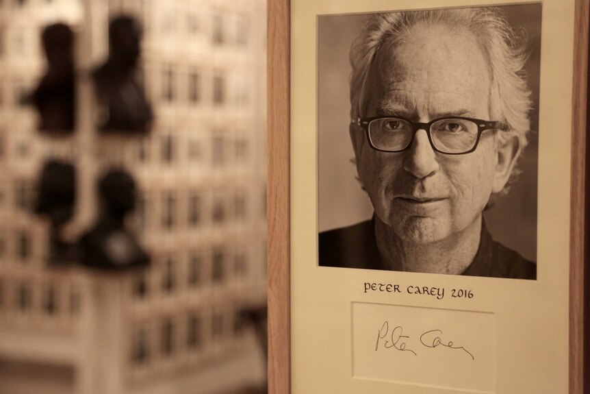 A photo of Peter Carey above a box with his signature sits in a picture frame.