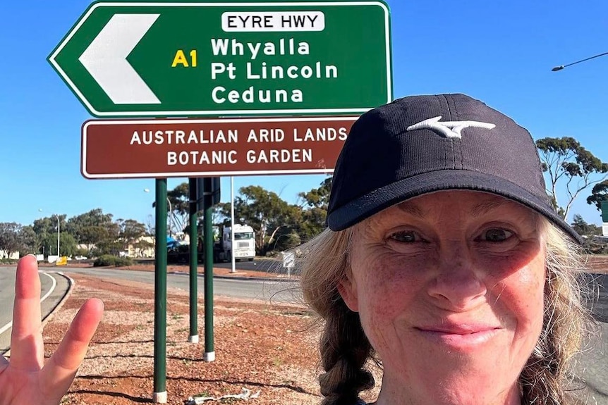 A woman taking a selfie in front of a road sign.