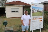 Haig Abraham standing next to a 'for sale' sign outside a house he is trying to sell.