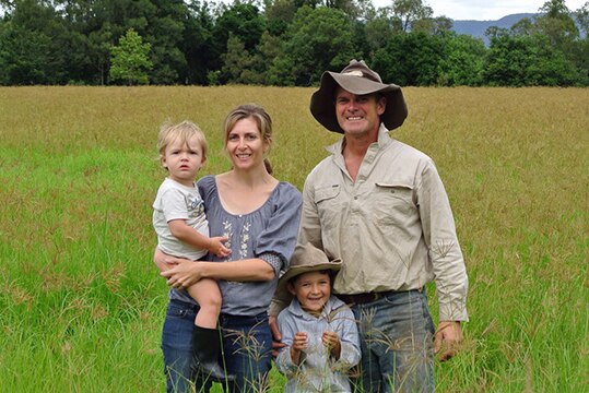 Karen Jarling and Warren McEwan with their two children standing in deep pasture.