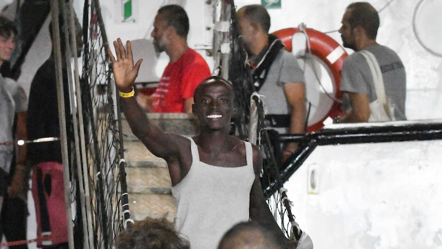 A man waves as he disembarks from the Open Arms rescue ship.