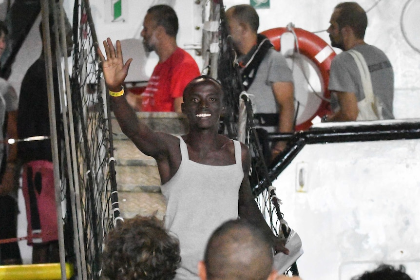 A man waves as he disembarks from the Open Arms rescue ship.