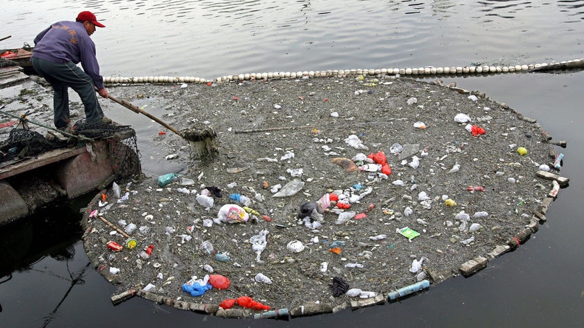 A Chinese workers clears away rubbish from a polluted river in Beijing. (File photo)