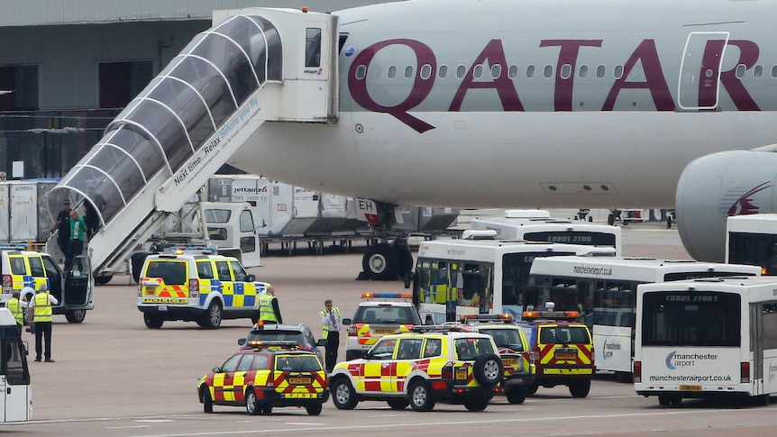 A man is escorted off the Qatar Airways plane by police at Manchester airport.