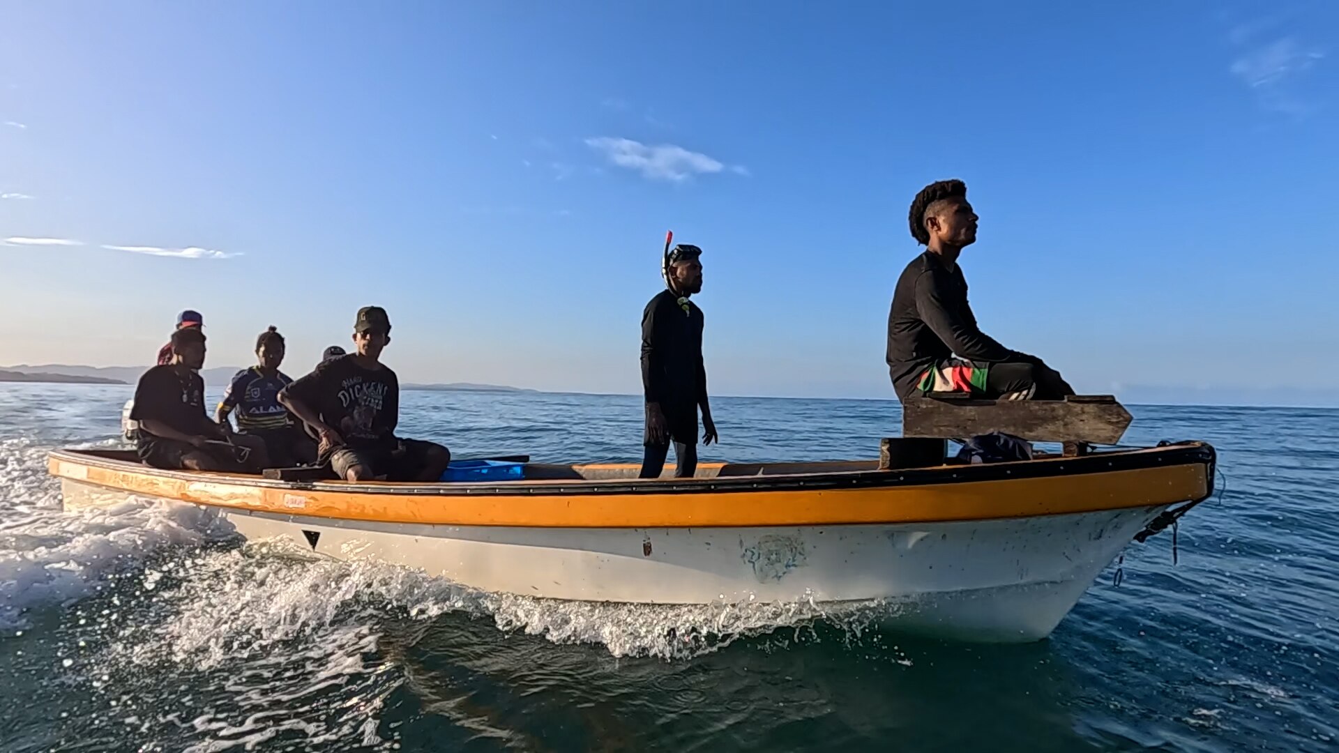 A group of men sit on top of a boat speeding through the water.