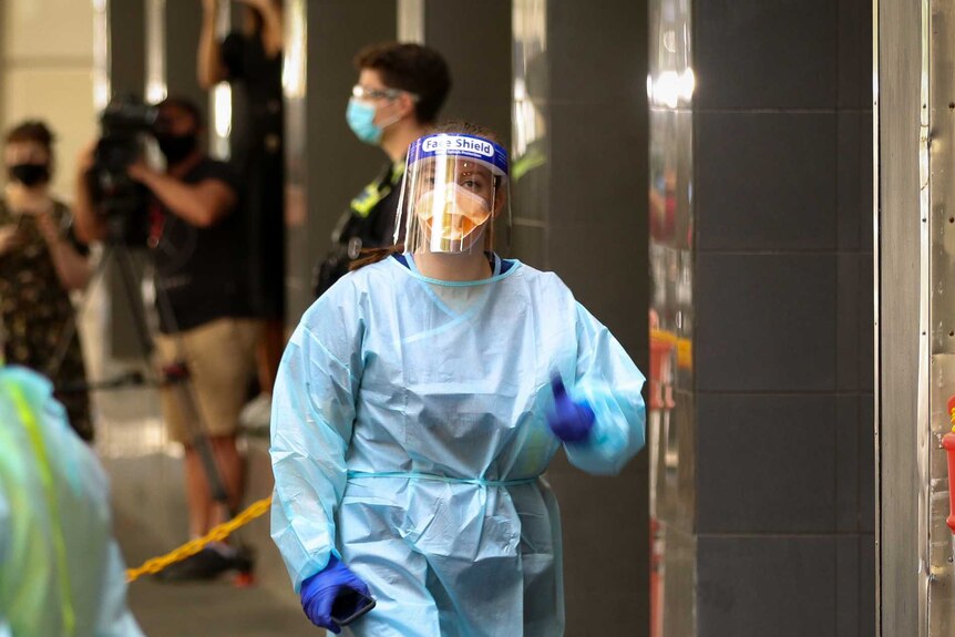 A hotel quarantine worker wears a blue gown, N95 mask and face shield.