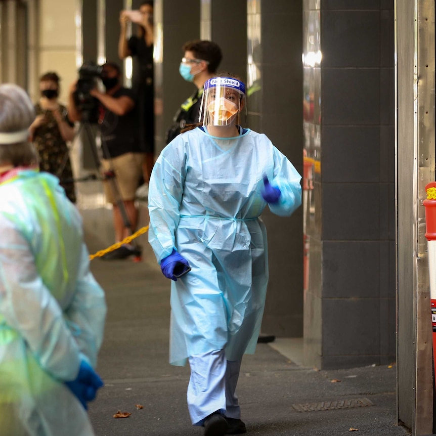 A hotel quarantine worker wears a blue gown, N95 mask and face shield.
