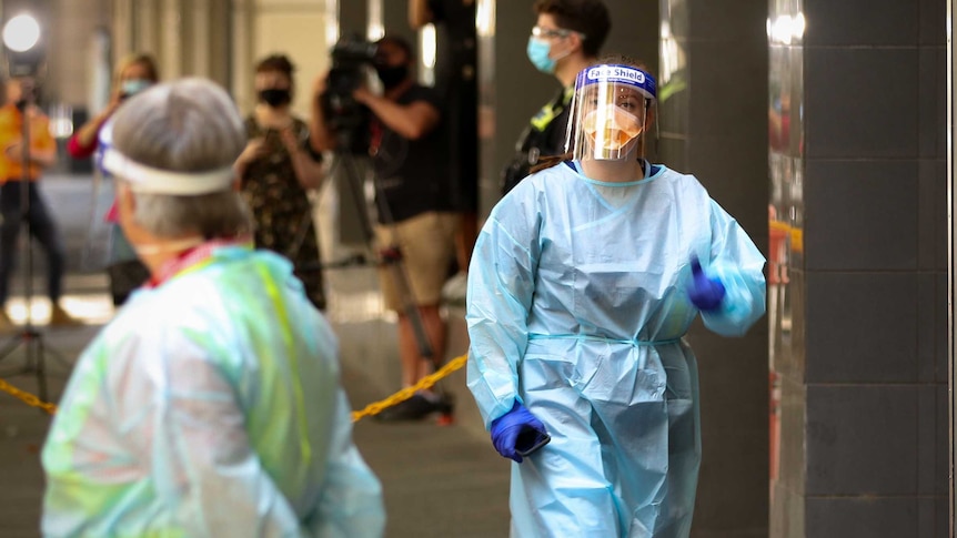 A hotel quarantine worker wears a blue gown, N95 mask and face shield.