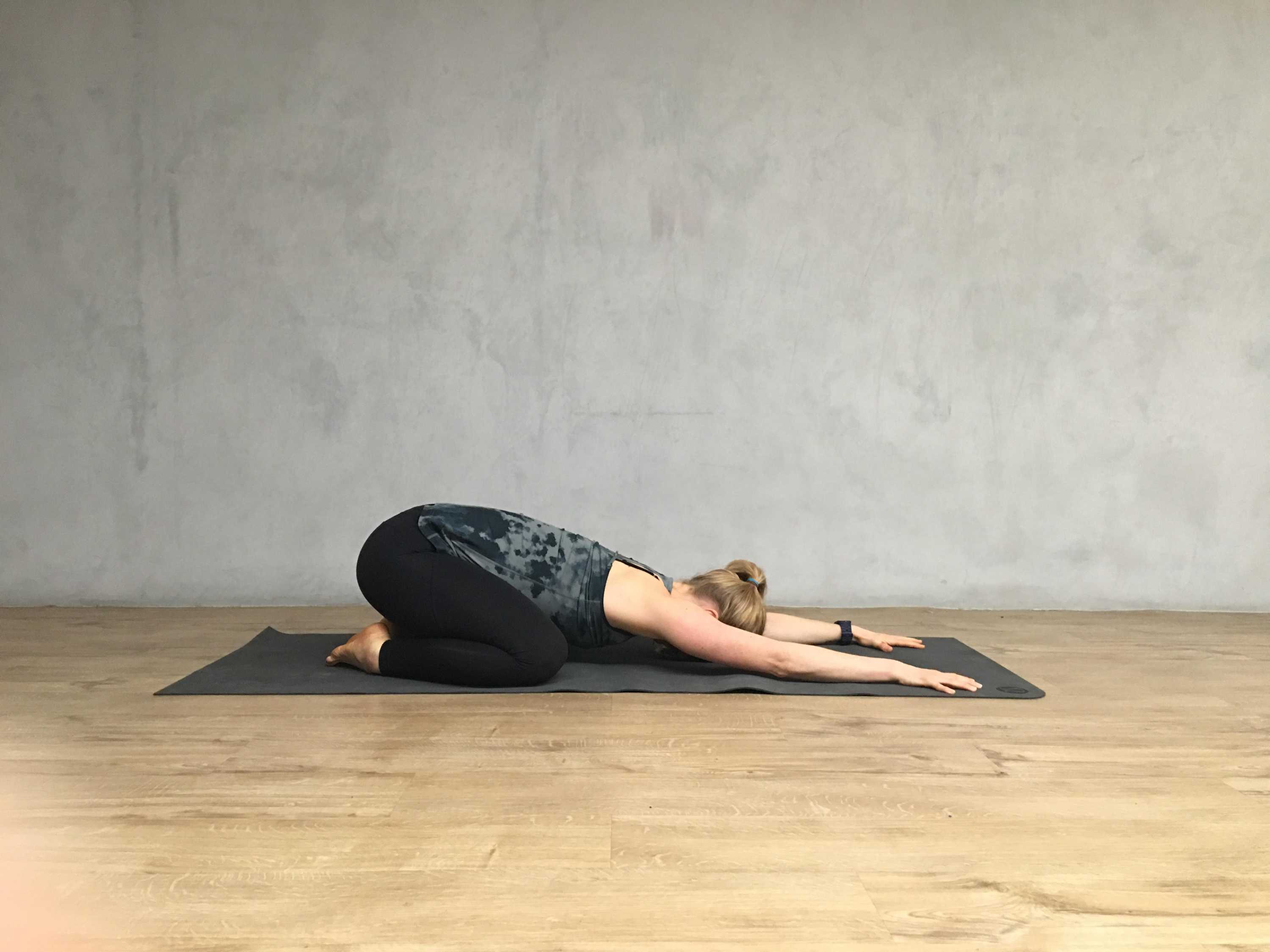 Ein Yogalehrer demonstriert die Kinderstellung.