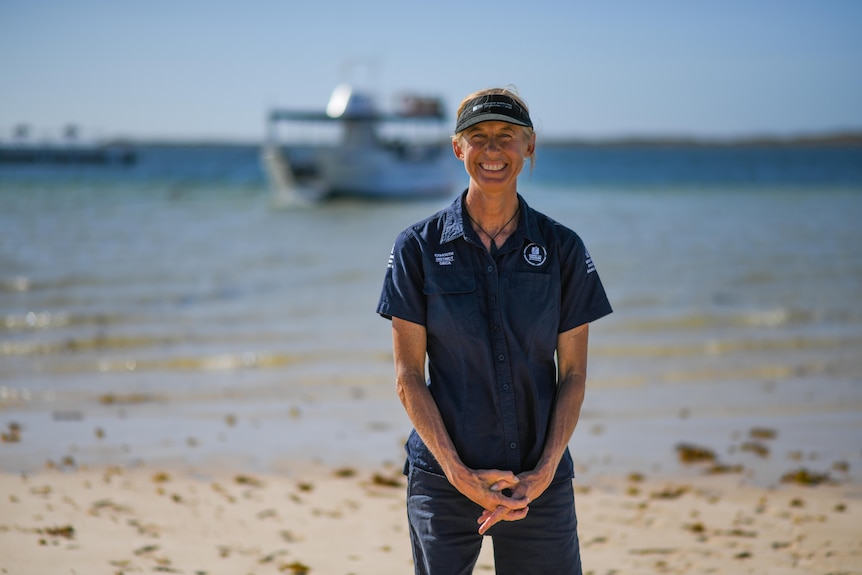  woman in blue visor stands on beach