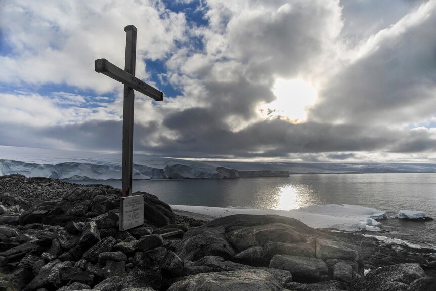 A wooden cross overlooks a body of water in Antarctica.