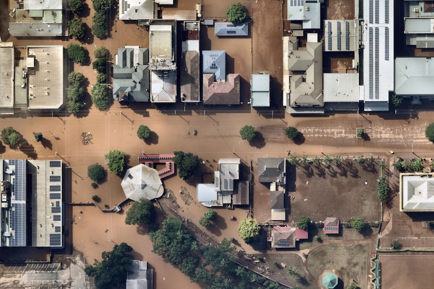 Many buildings along the main street of Lismore are surrounded by floodwaters, as seen from above.