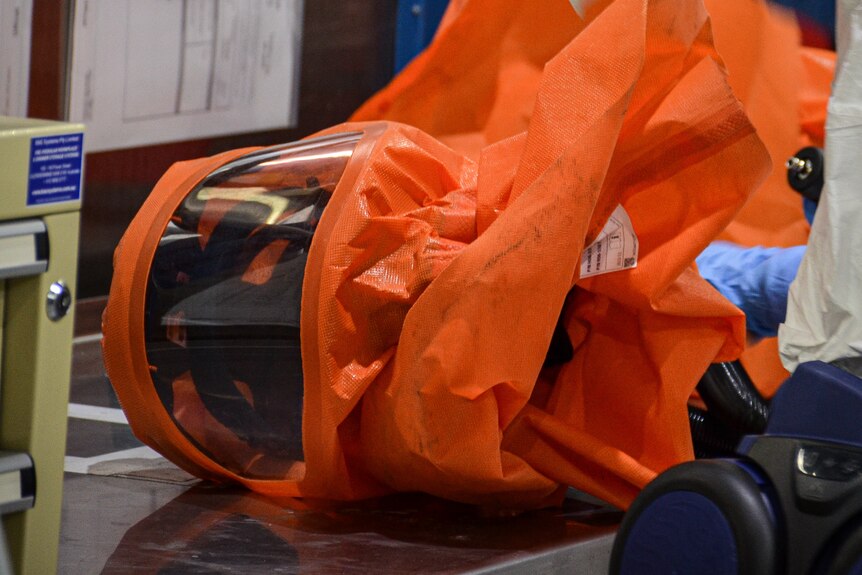 The orange plastic hood is lying on its side on a table