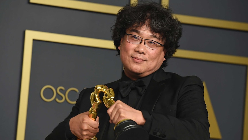 Bong Joon Ho makes his two Oscar statues kiss at the Academy Awards ceremony.